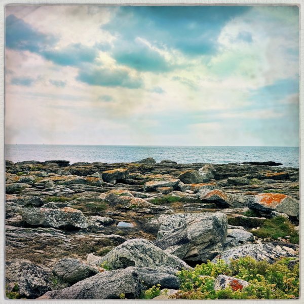 Photographie de rochers devant l'océan. Couleurs pastels et cadre de photo ancienne.