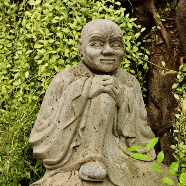 une statue de moine assis la tête posée sur les mains