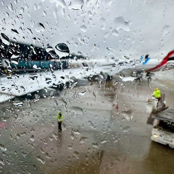 Depuis les fenêtres de l'avion, vue sur le tarmac à travers les gouttes de pluie sur les vitres.