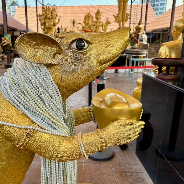 Statue d'un rat doré se tenant debout qui porte des offrandes et des bijoux à Ganesh dans ses pattes avant.