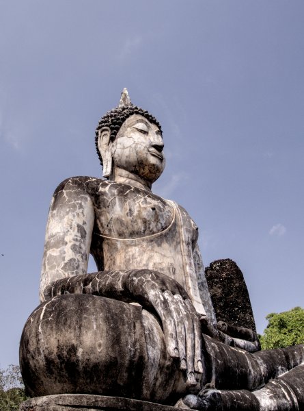 Un grand bouddha assis, en marbre blanc noirci par le temps.