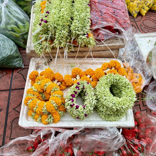 Des fleurs fraiches tressées et en couronnes devant le marché aux fleurs.