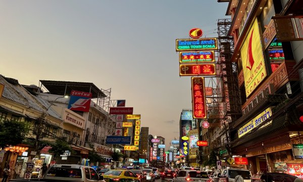 La circulation intense et les enseignes lumineuses dans Chinatown à la tombée de la nuit.