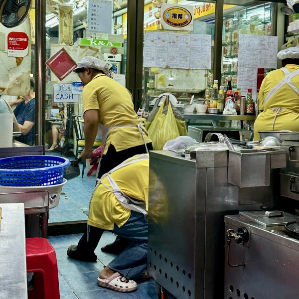 Des femmes vêtues de vêtements de travail jaune s'affairent dans la cuisine vitrée d'un restaurant.
