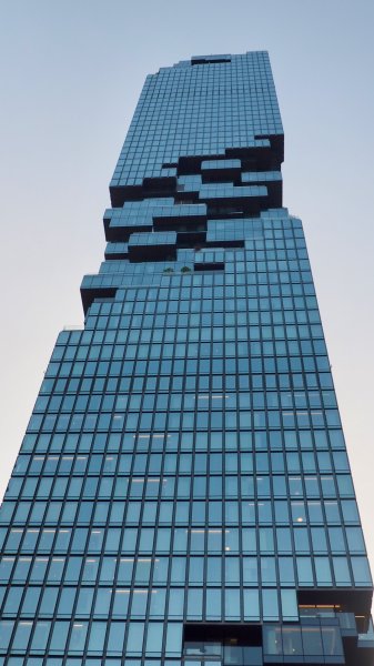 Une grande tour moderne et vitrée, photographiée en contre-plongée. La façade est formée de cubes comme des pixels qui sont en partie manquants ou décalés.