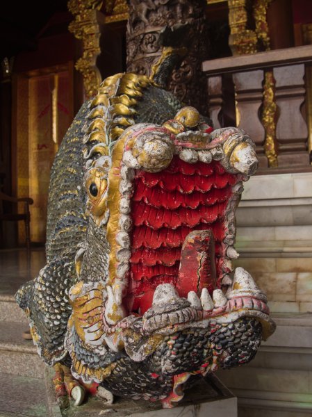 Une gueule ouverte de nāga sculpté sur un escalier. Il est peint de couleurs vives, l'intérieur de la gueule est très rouge.