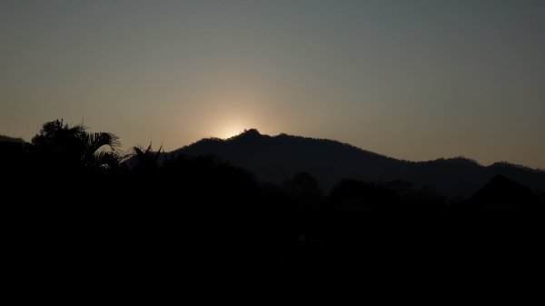 Une montagne et des palmes en ombre chinoise au coucher de soleil