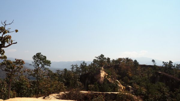 Un chemin de terre ocre qui serpente et se perd au sommet de la montagne.