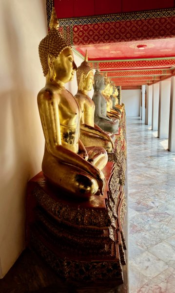 Des bouddhas dorés, assis et alignés dans une des salles avant le grand Bouddha assis