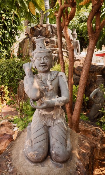 Une statue en pierre dans le jardin qui a une attitude rigolote, un genre de bras d'honneur raté. C'est en fait une posture de yoga qui est représentée.