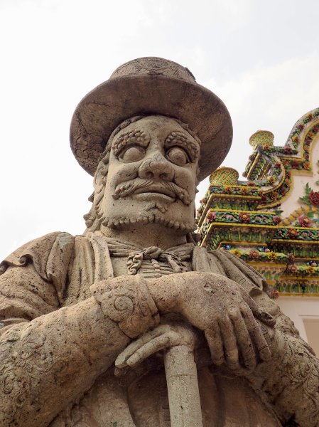Gros plan sur le visage d'une statue en pierre avec un chapeau et de gros yeux.