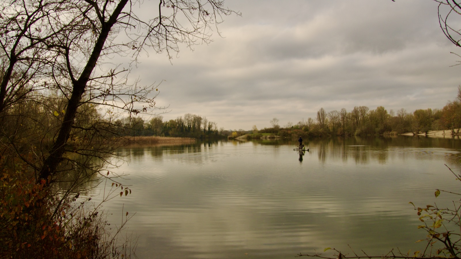 Paysage d'automne. Une barque au milieu de l'eau lisse et les berges dorées.